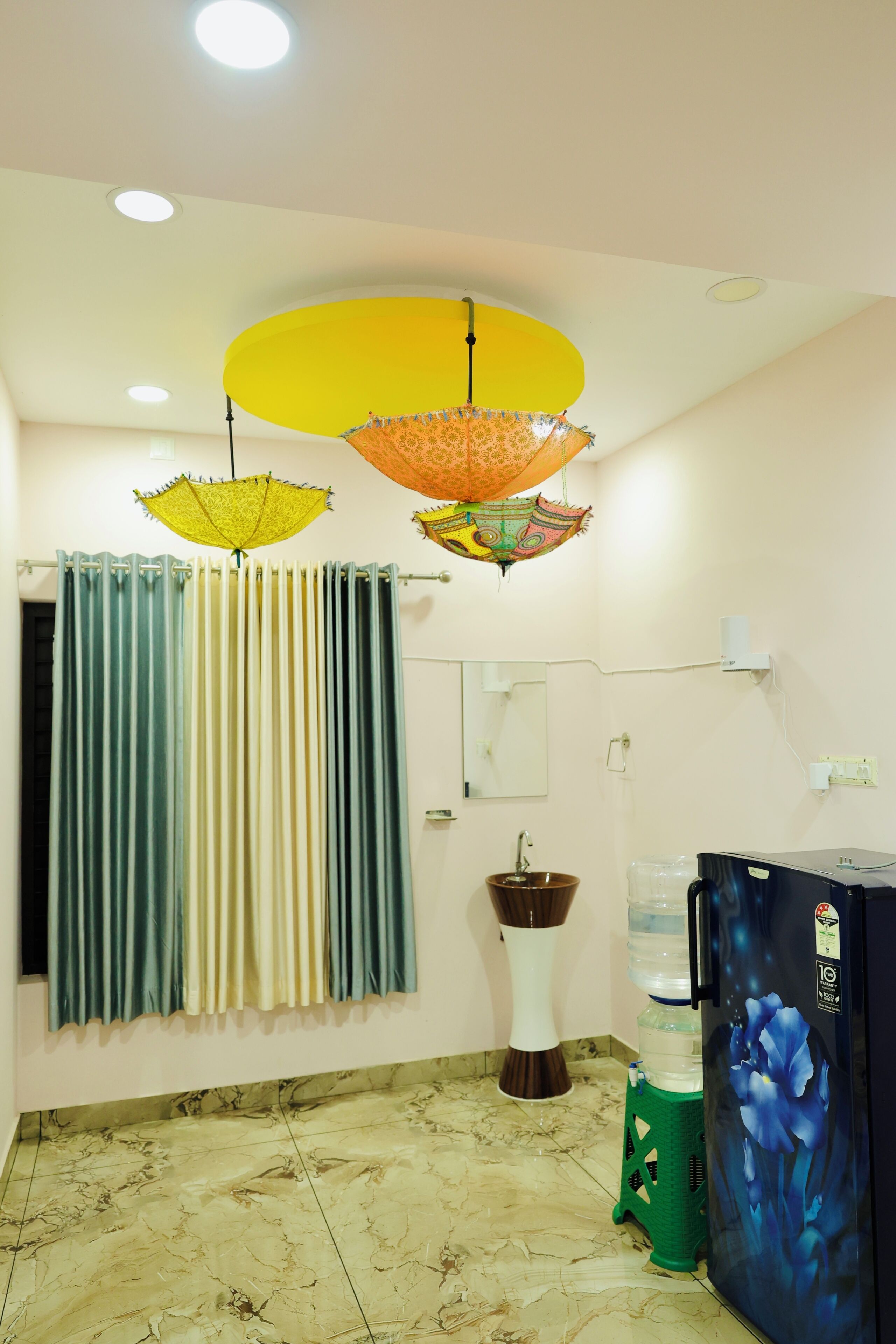 A room with a bathroom, a water dispenser, a refrigerator, and a curtain.