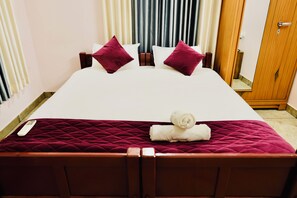 Habitación de hotel con cama, almohadas, un armario de madera y un espejo.