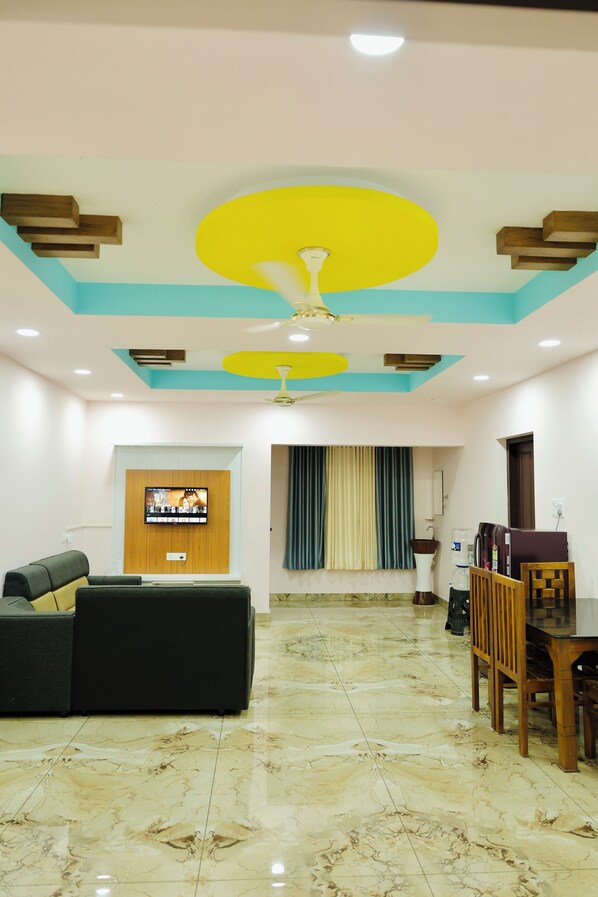 A living room with a TV, sofa, and dining area. - Varkala Escape Resorts (Varkala)