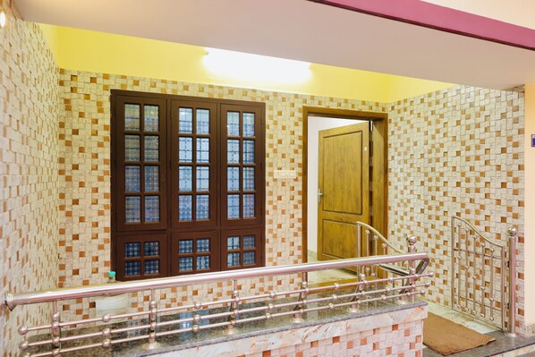 Un escalier avec une rampe métallique, une porte en bois et un mur orné de motifs de carreaux.