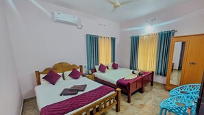 A hotel room with two wooden beds, a ceiling fan, a mirror, and a blue chair. - Varkala Escape Resorts (Varkala)