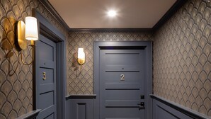 A hallway with two doors, one labeled '3' and the other '2', and a wall-mounted light fixture. - Shelburne Springs Hotel (Shelburne)