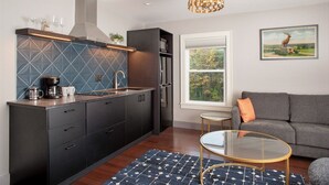 A modern kitchen with dark cabinetry, a coffee machine, and a built-in stove. - Shelburne Springs Hotel (Shelburne)