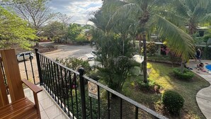 Un balcón con vistas a un jardín, una piscina y una carretera.