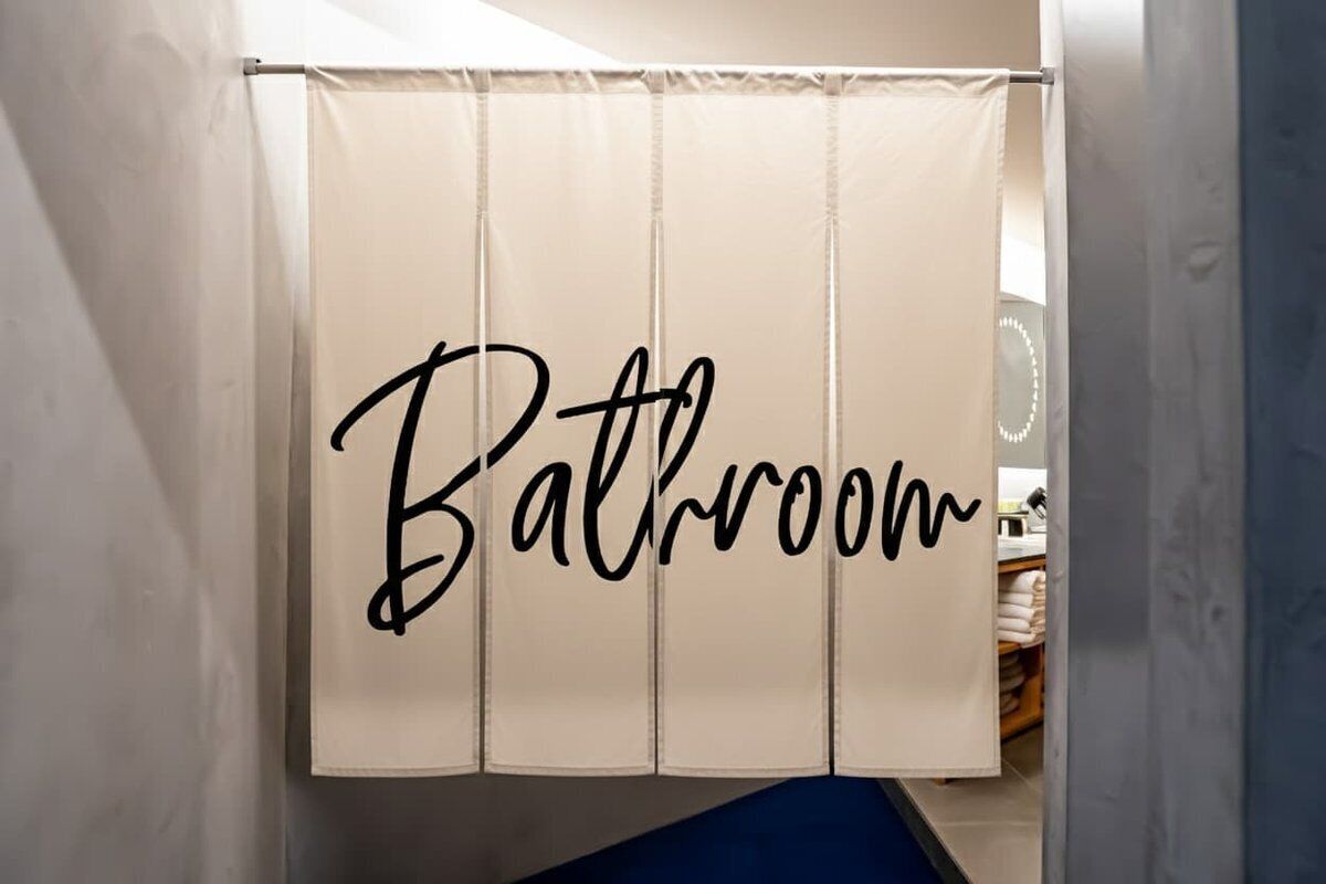 A bathroom with a curtain that has 'Bathroom' written on it.