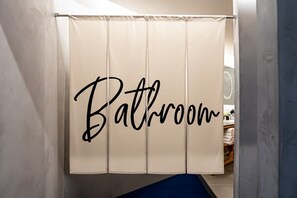 Ett badrum med en duschdraperi där det står ”Badrum” på den.