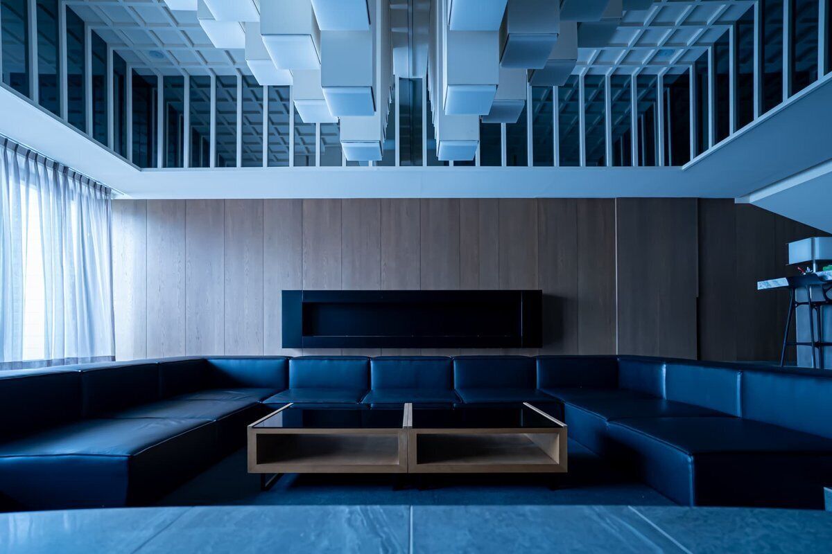 A modern living room with a sectional sofa, a flat-screen TV mounted on the wall, and a wooden panel accent wall.