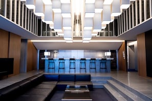 A modern interior with a bar area, seating, and a staircase.