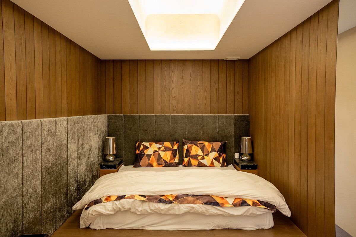 A bedroom with a bed, two bedside tables, and a skylight.