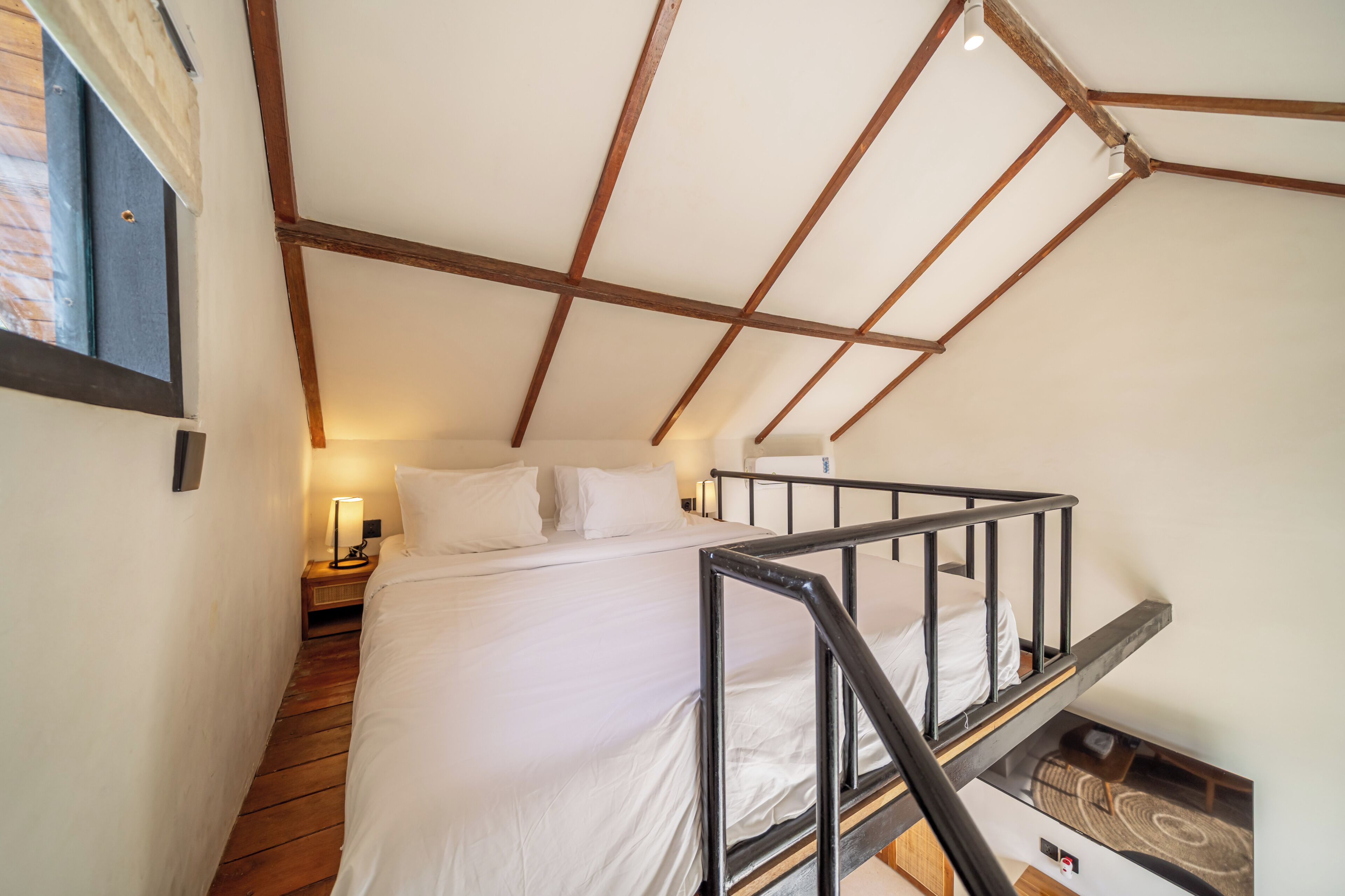 Un dormitorio con literas, vigas de madera, una mesita de noche y una lámpara.