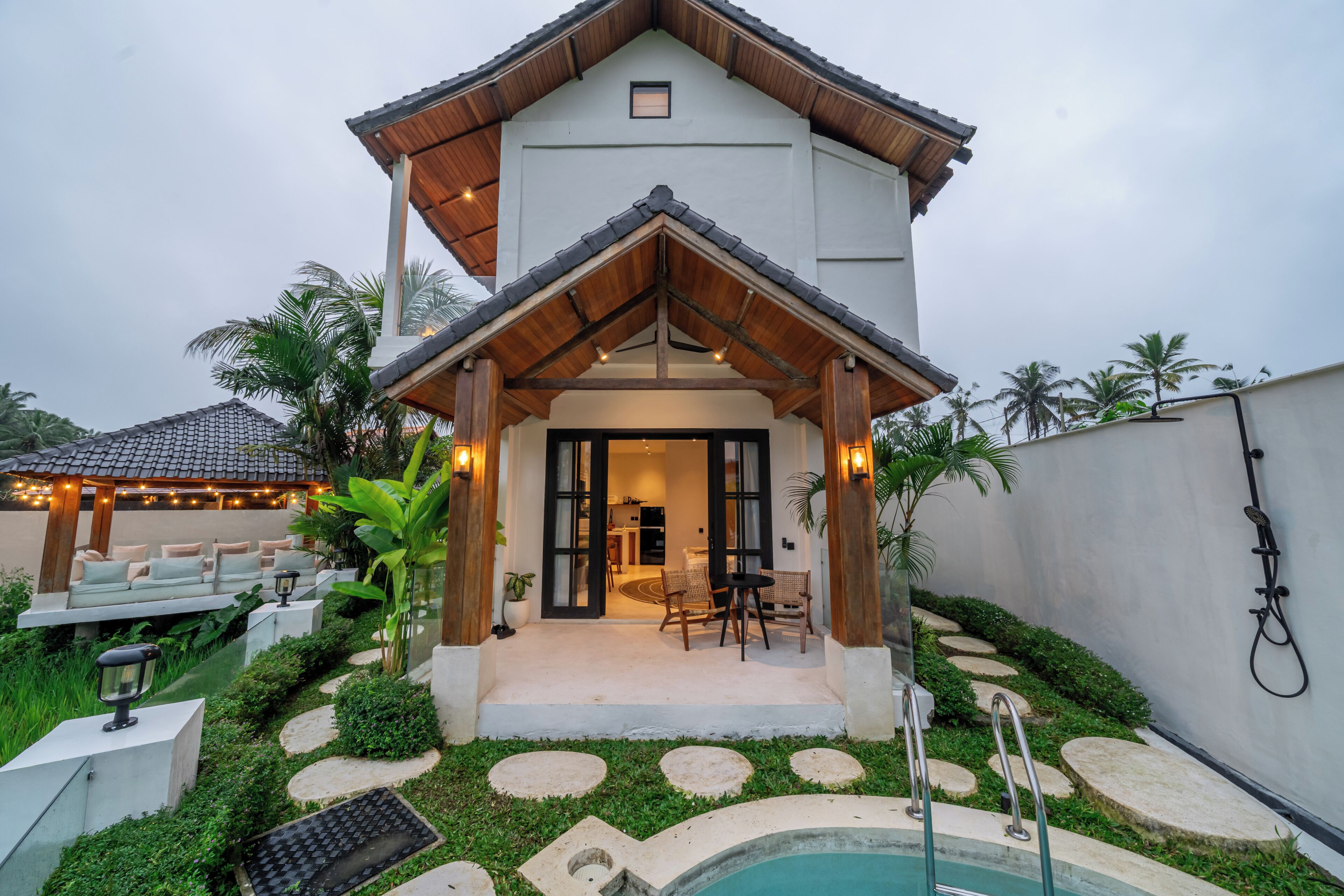 A modern house with a pool, outdoor seating, and a covered patio area.