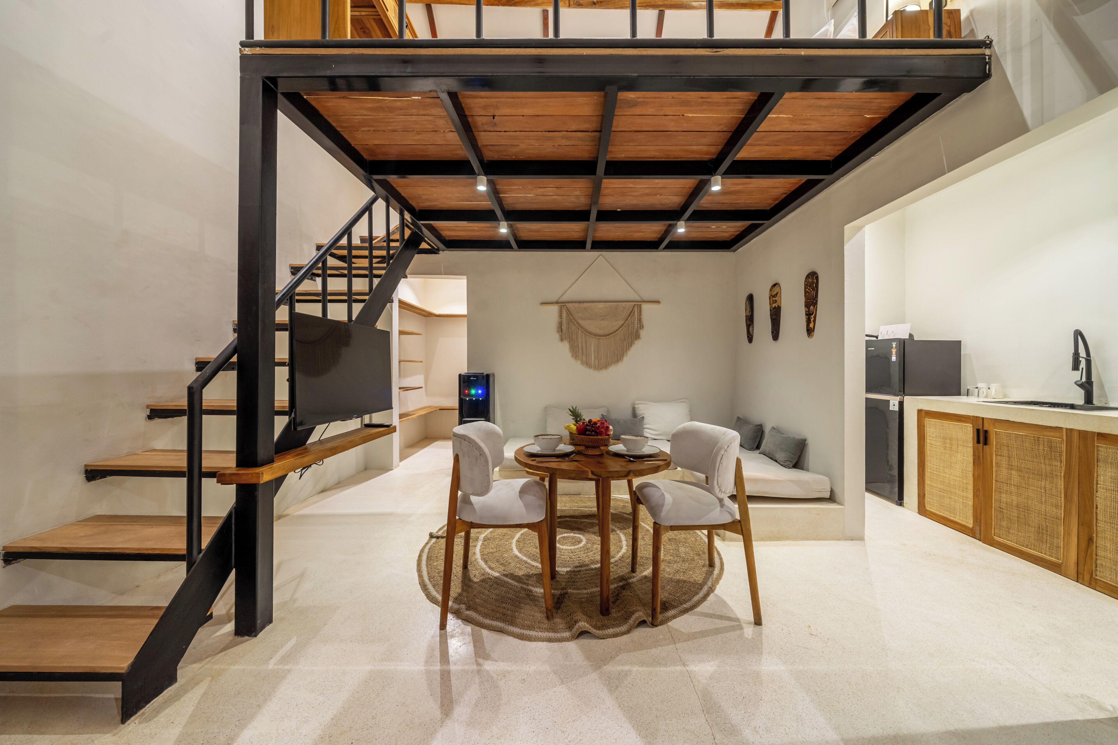 A modern interior with a staircase, dining area, kitchen, and living space.
