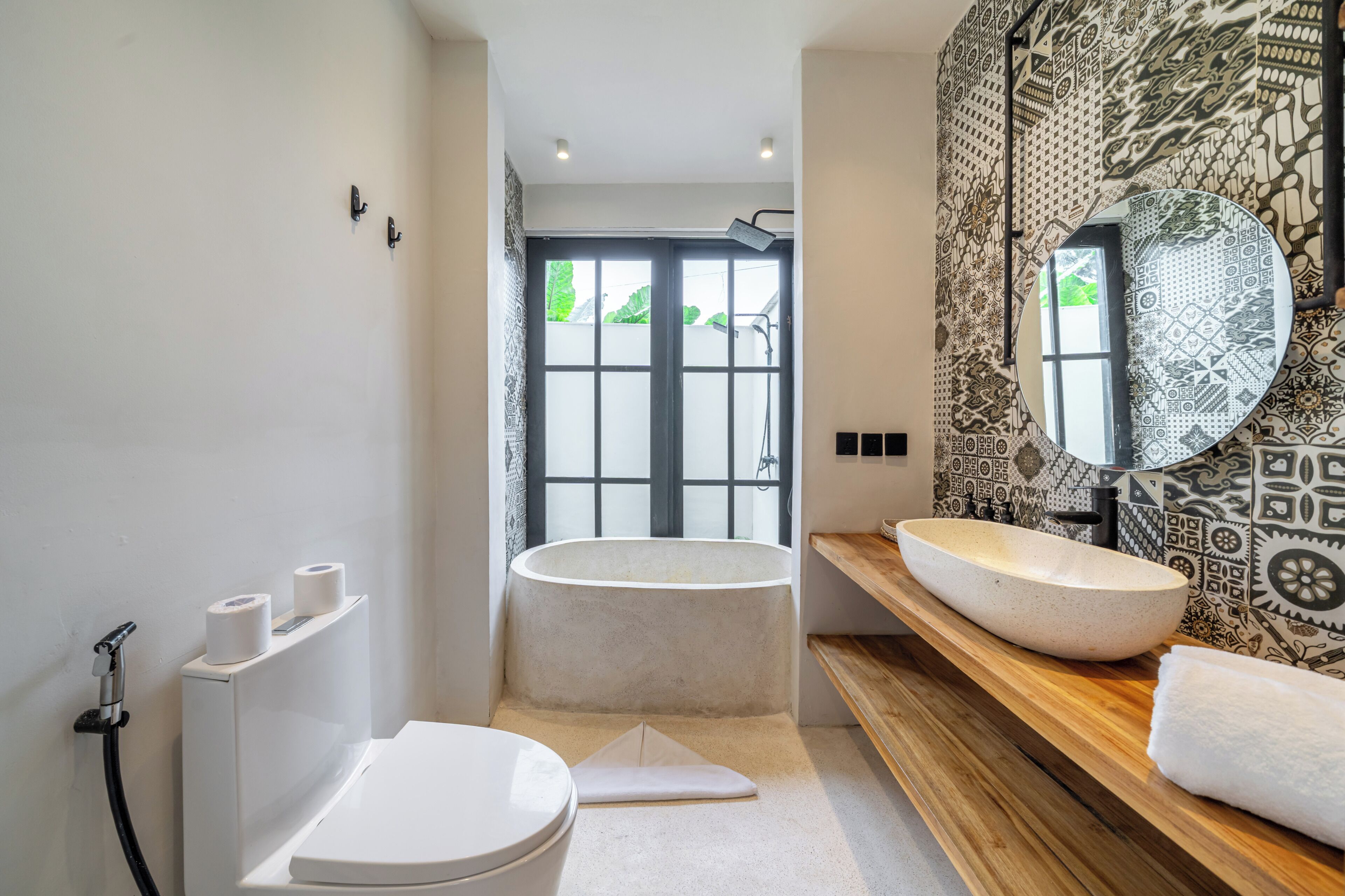 A modern bathroom with a freestanding bathtub, a large mirror, and a wooden vanity.