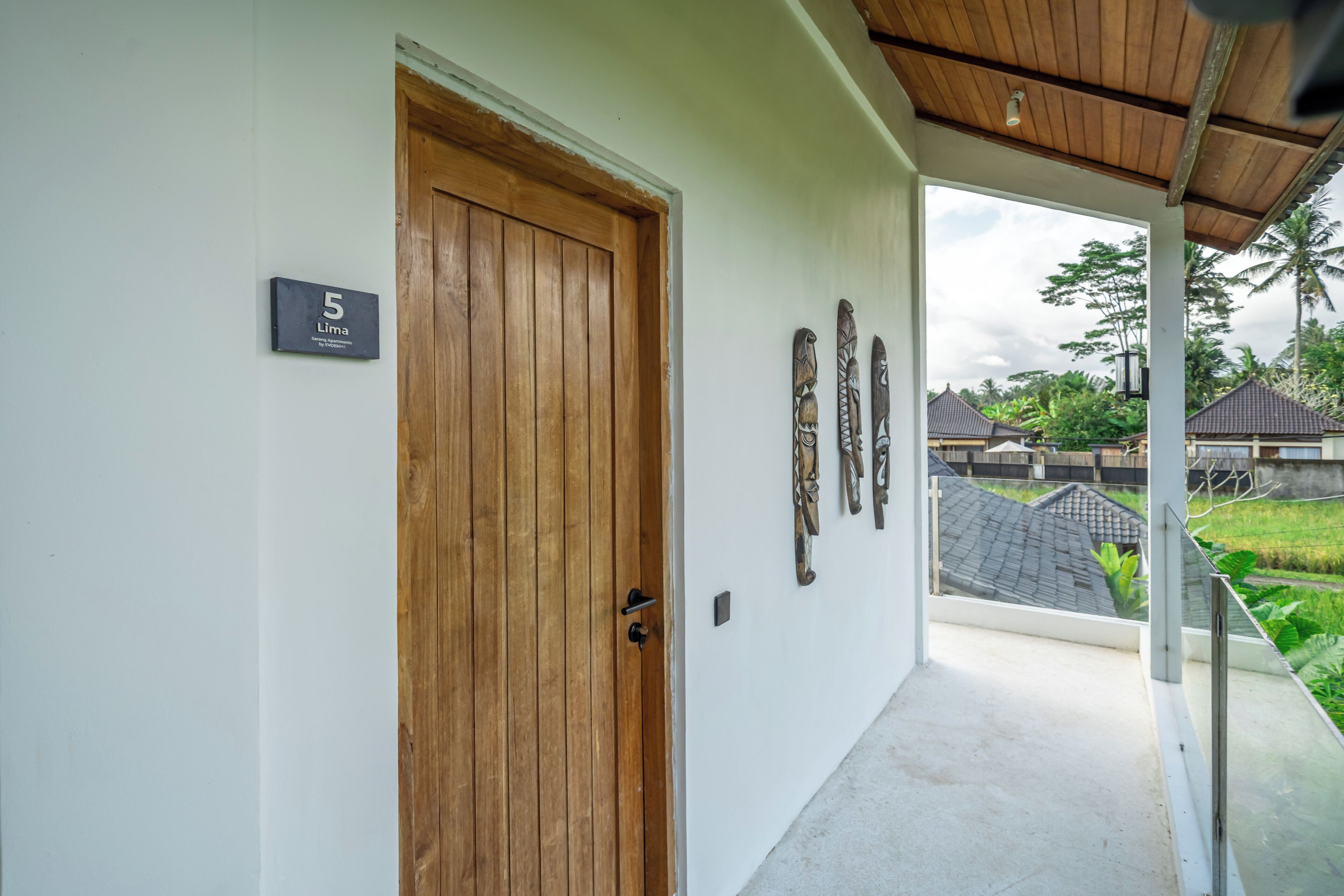 A hallway with a wooden door, a number sign, and wall-mounted decorations.