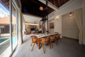 Un comedor con vista a la piscina, sillas de madera, una gran mesa de comedor y una escalera.