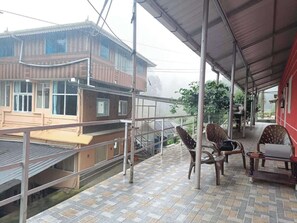 Un espacio al aire libre cubierto con vistas a un edificio, una barandilla y dos sillas.