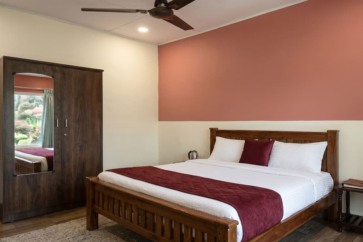 Un dormitorio con cama de madera, armario, ventilador de techo y vista a un jardín.