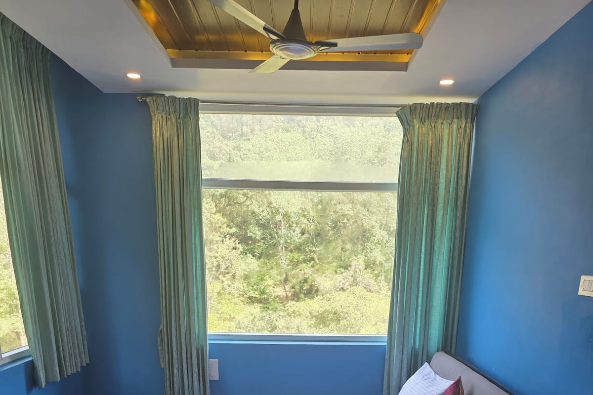 Una cama con un edredón rojo, almohadas blancas y piso de madera.