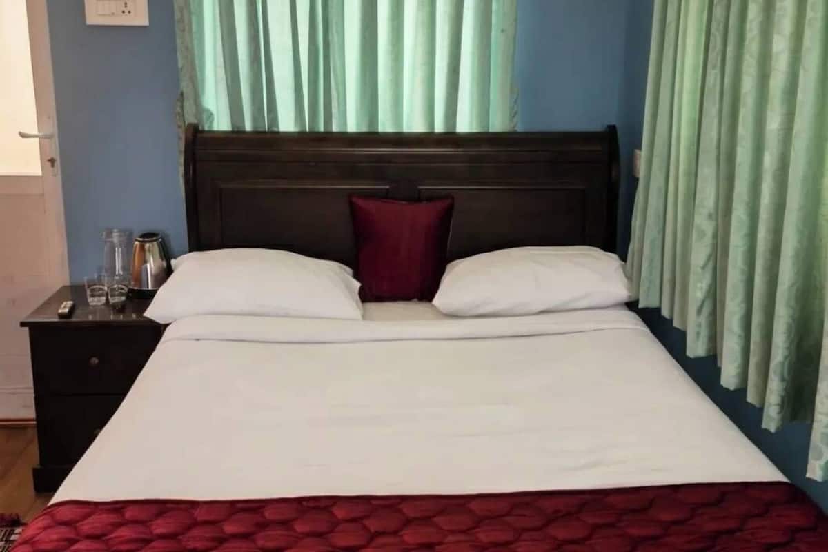 Una cama con cabecera de madera, una manta roja y una almohada roja.