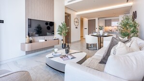 Una sala de estar moderna con un sofá curvo, una mesa de centro con revistas, un televisor y un diseño minimalista.