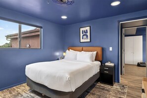 A bedroom with a bed, a nightstand, a framed picture, a window, and a door. - Sedona Stay • Balcony • Near Trails + Dining + Red Rock Views | Canyon Drift (Sedona)