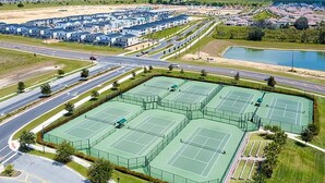 Suuri urheilukeskus, jossa on useita tenniskenttää, ja jonka ympärillä on asuinalueita ja tie.