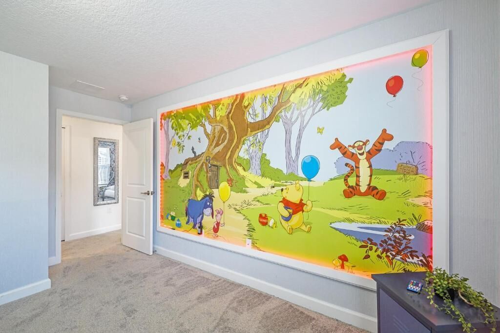 Ein Flur mit einem großen Wandbild von Winnie Puuh, einer Tür und einer Pflanze auf einem Beistelltisch.