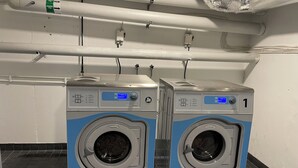 Dos lavadoras Electrolux de carga frontal en un entorno comercial, con tuberías y paneles de control visibles.