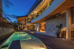 Ein modernes Haus mit Swimmingpool, Holzterrasse und Steinmauern.