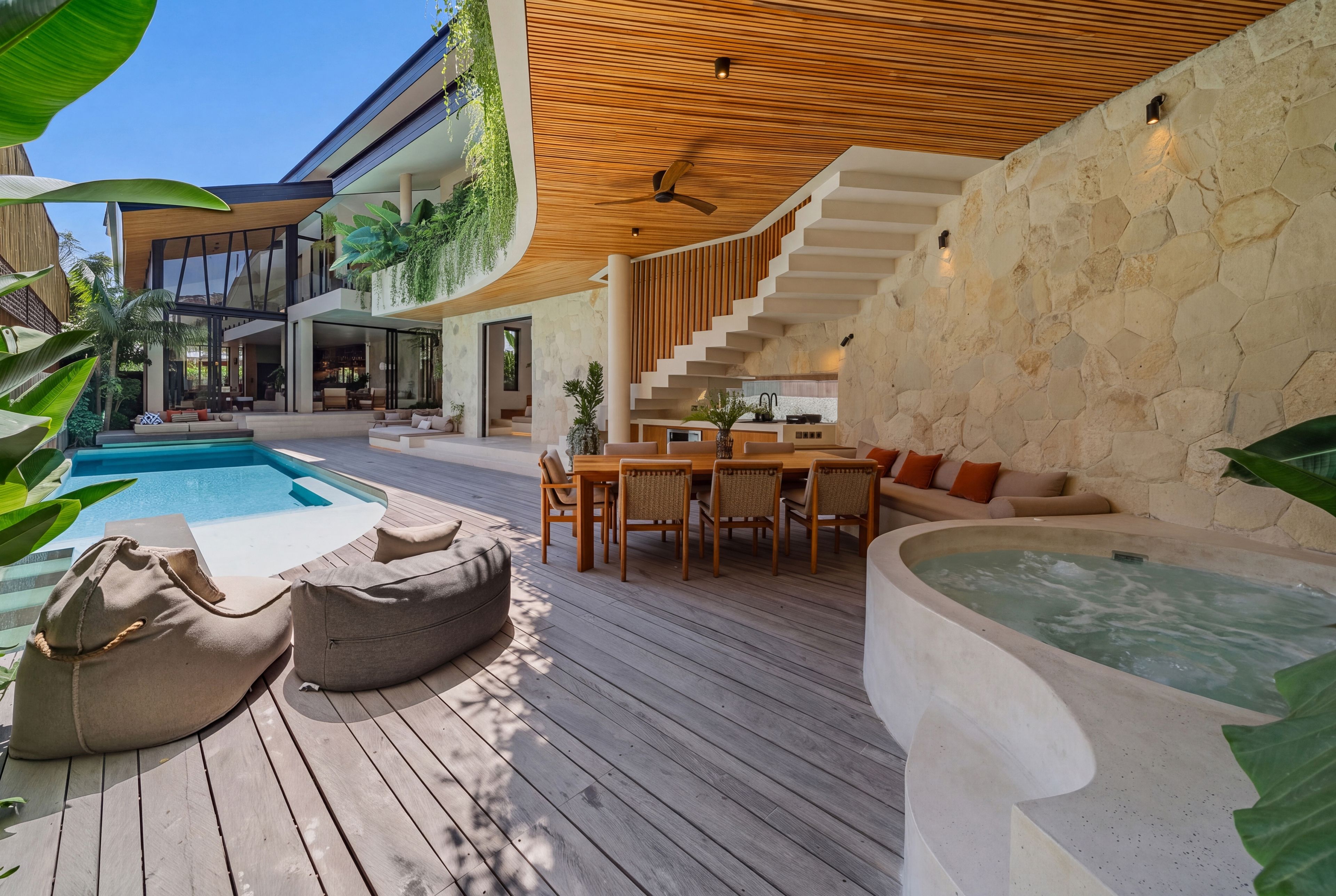 A modern outdoor living area with a pool, seating, and a hot tub.