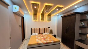 A bedroom with a bed, a wardrobe, a shelf unit, and a ceiling light fixture.