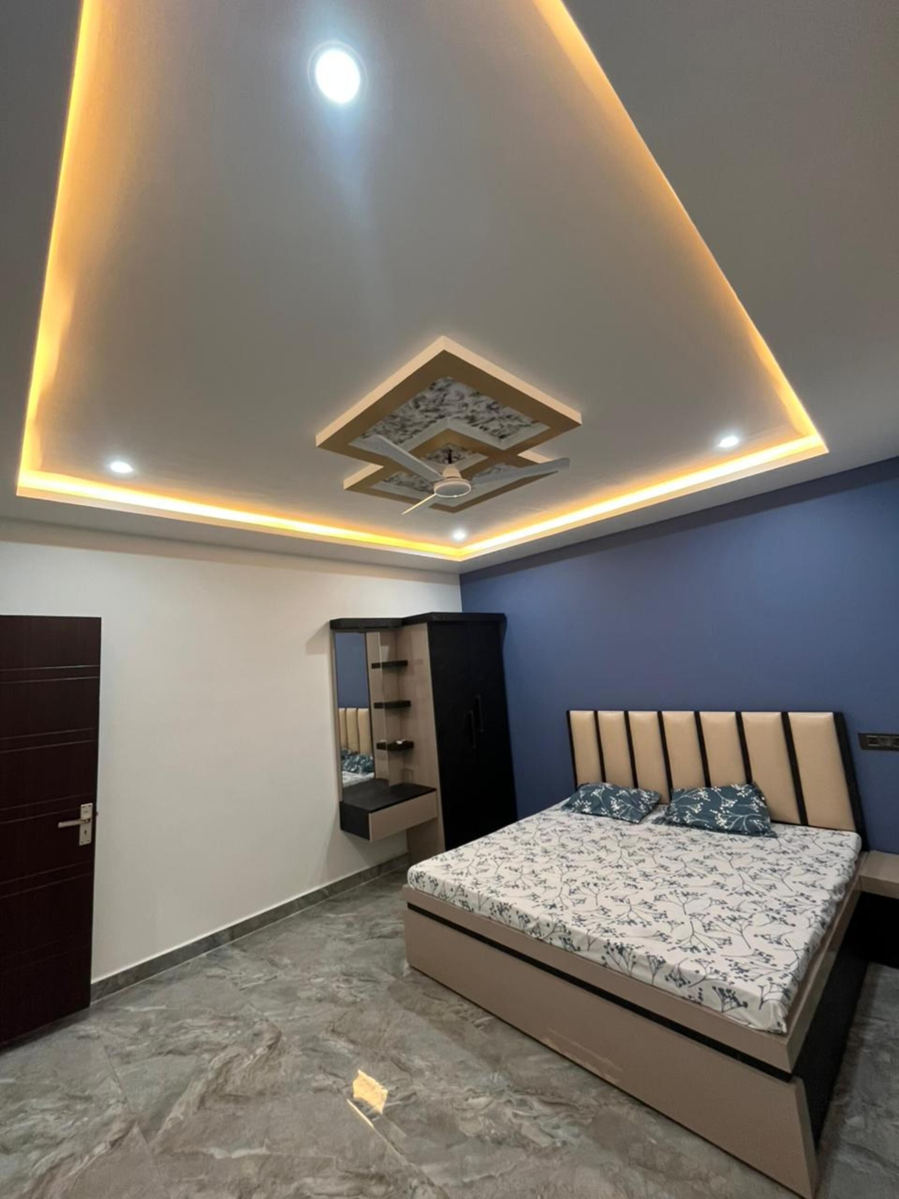 Un dormitorio con cama, armario, espejo e iluminación empotrada en el techo.