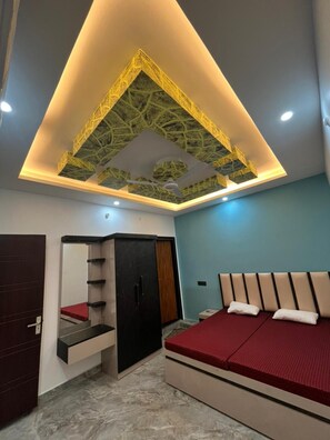 A bedroom with a bed, a wardrobe, a mirror, and a ceiling with a geometric design.