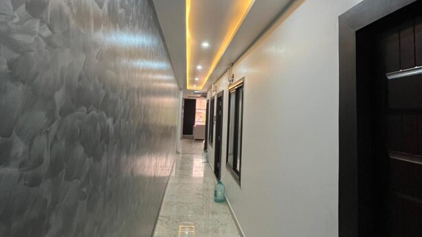 A hallway with a marble floor, recessed lighting, and a textured wall.