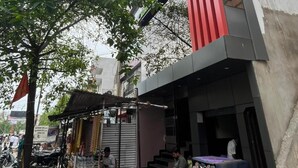 A building with a sign reading 'SCHOOL OF FASHION' and a small shop with a sign 'CANCER'.