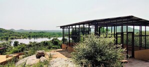 Una estructura cubierta de vidrio con vista a un lago y colinas.