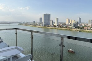 Uma varanda com vista para um rio, horizonte urbano e uma ponte.