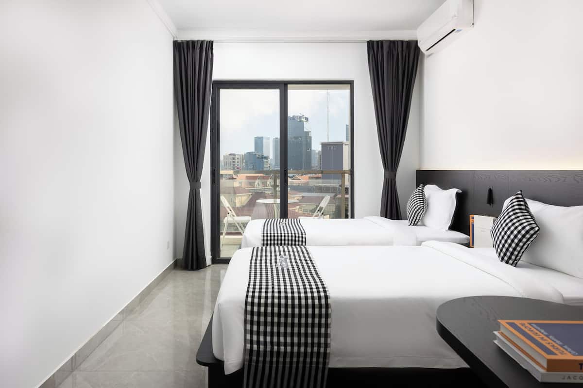 A hotel room with two beds, a view of the cityscape, and a modern design.