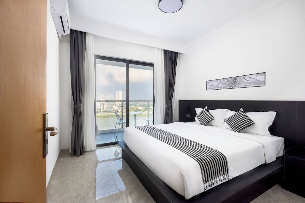 A hotel room with a large bed, a view of the city, a balcony, and a modern design.