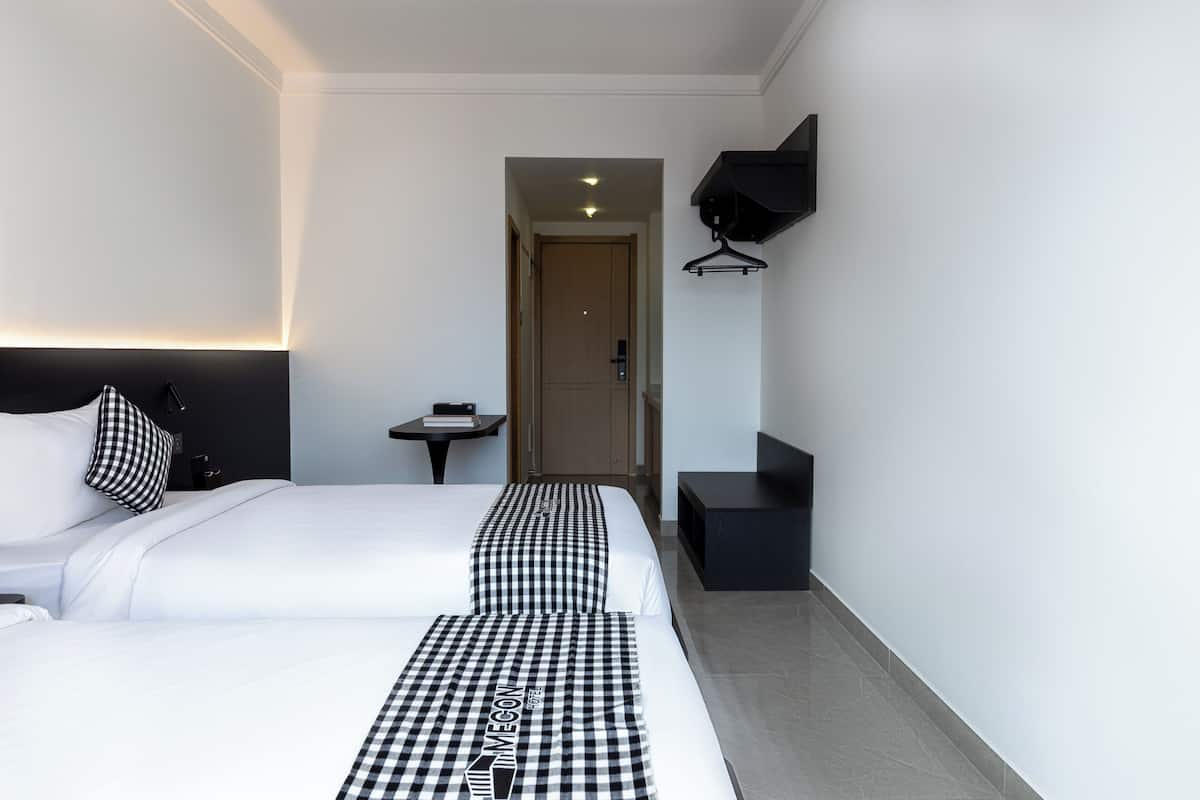 A hotel room with a bed, a bedside table, a TV, and a coat rack.