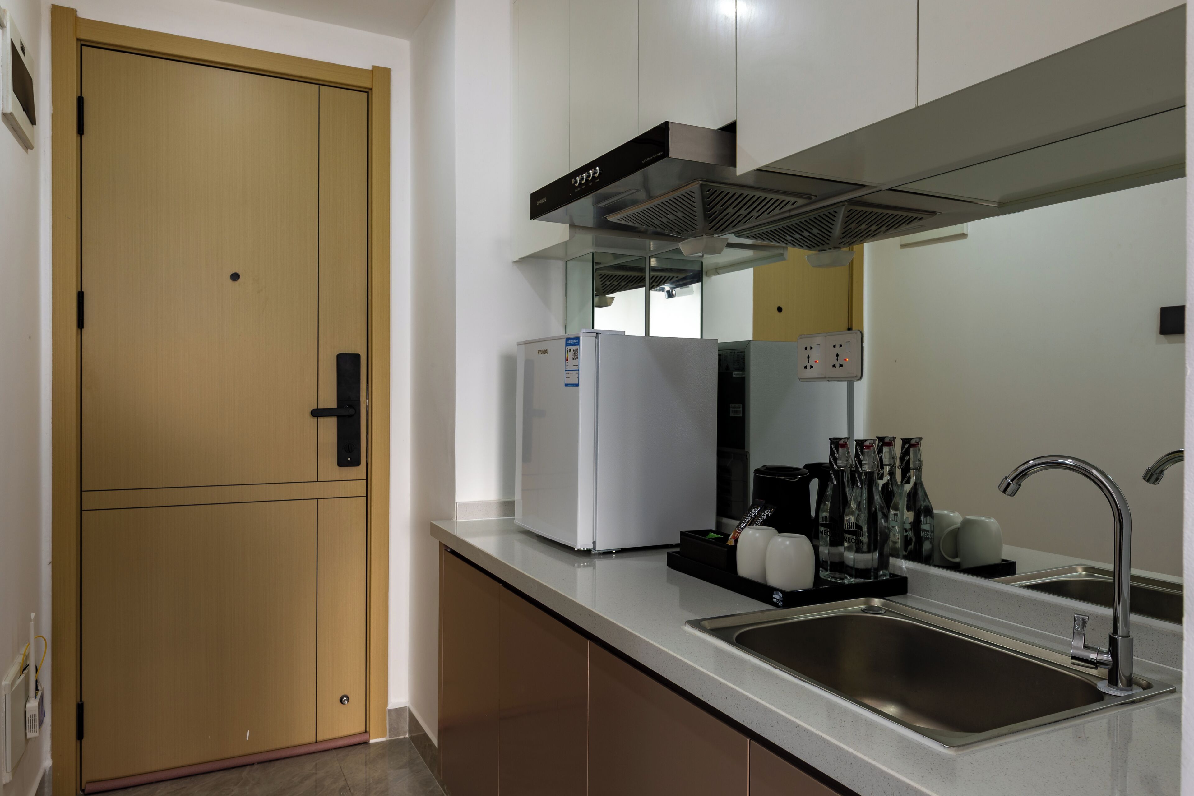 A kitchen with a double door, a built-in refrigerator, a sink, and a range hood.