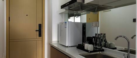 A kitchen with a double door, a built-in refrigerator, a sink, and a range hood.