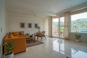 Un salón amplio con sofá, sillones, una mesa de centro y vistas a una piscina a través de amplios ventanales.
