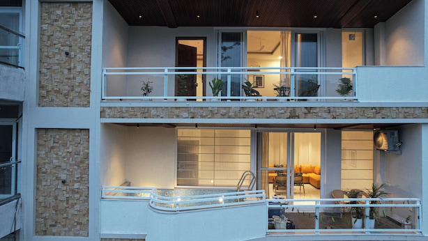 A multi-story building with balconies, a pool area, and a dining space. - Alaya Stays Udgam Vilas 3-BHK With Lift (Dehradun)