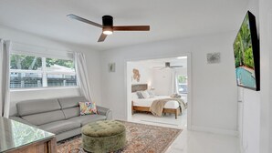 A modern living room with a sofa, ottoman, and a large rug.