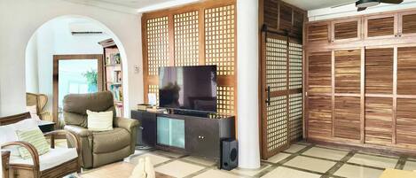 Sala de estar com sofá, poltrona, mesa de centro, televisão e um separador decorativo.