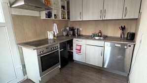 A compact kitchen with a stove, oven, microwave, and dishwasher.