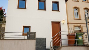 A two-story building with a white facade, brown trim, and a set of stairs leading to the entrance.