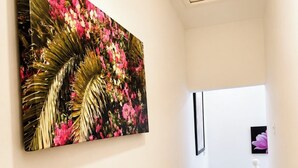 A hallway with a staircase, a wall-mounted painting, and a door at the end.