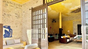 A room with a stone wall, a wooden sofa, a glass coffee table, and a large sliding door leading to another room.